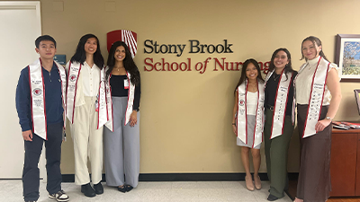 SBSNA students standing in front of a School of Nursing sign.